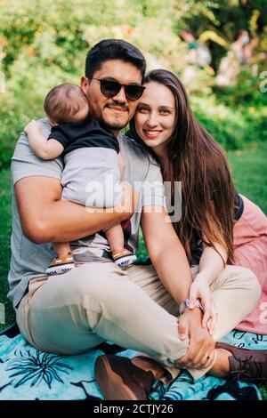 Happy young family sitting at park while enjoying weekend Stock Photo