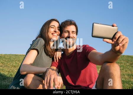 Man taking selfie with woman while sitting on grass Stock Photo