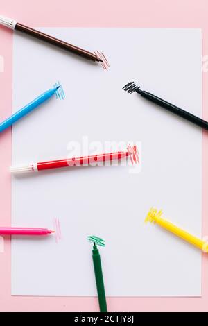 Colorful felt tip pens on white paper over colored background Stock Photo