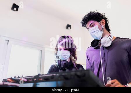 Couple wearing face masks while mixing techno sound at recording studio Stock Photo