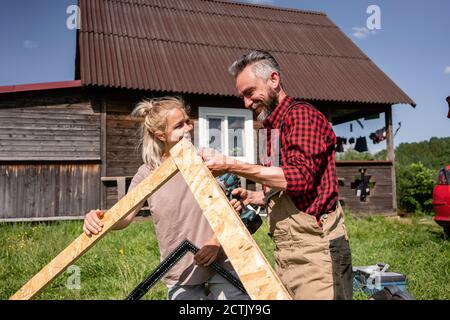 Carpenter and woman working together to make house for children on sunny day Stock Photo