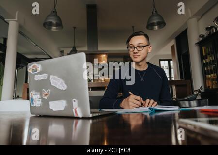 Young man studying from home, using laptop Stock Photo