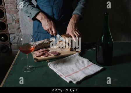 Midsection of man cutting homemade bread on board at table Stock Photo