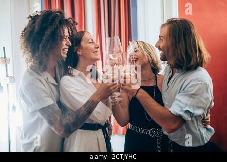 Cheerful male and female friends toasting wineglasses during party at home Stock Photo