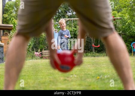 Boy playing soccer with father on grass at back yard Stock Photo