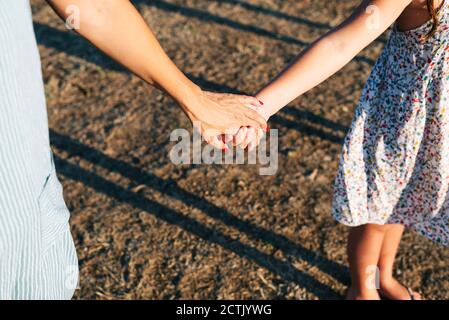 Mother holding daughter's hands while standing on land Stock Photo