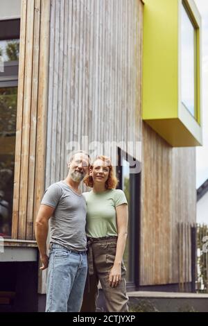 Thoughtful couple looking away while standing against tiny house in yard Stock Photo