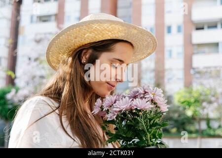 Beautiful woman smelling bouquet of fresh pink flowers at springtime Stock Photo