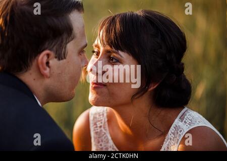 Close-up of bridal couple looking at each other during sunset Stock Photo