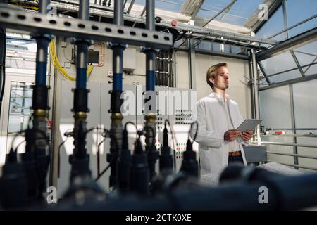 Scientist with closed eyes holding tablet in a greenhouse Stock Photo