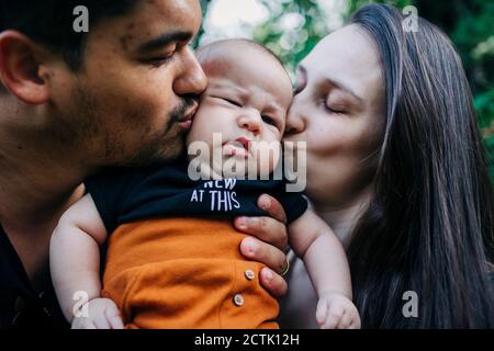 Young parents kissing baby boy Stock Photo