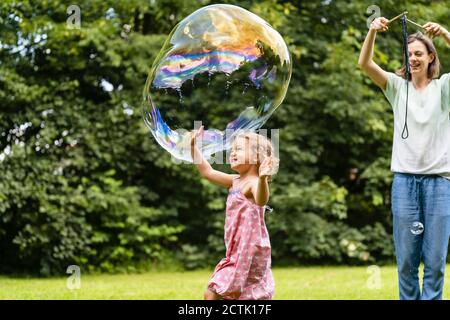 Mother and daughter playing with bubble at park Stock Photo