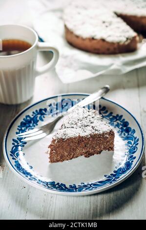 Slice of chocolate fridge tart with coconut shreds and mug of coffee Stock Photo