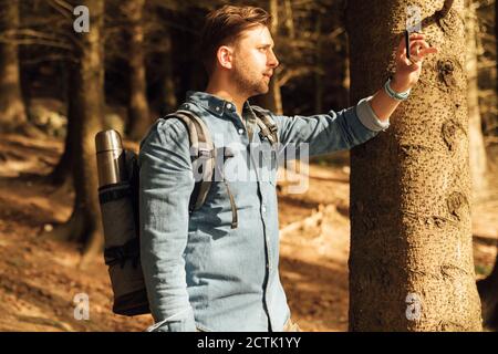 Mid adult man photographing with mobile phone while standing in forest Stock Photo