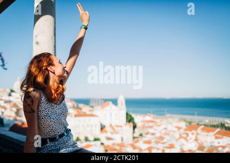 Young woman sitting and gesturing peace sign at Alfama, Lisbon, Portugal Stock Photo