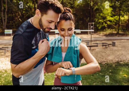 Sporty man and woman looking at a smartwatch in a park Stock Photo