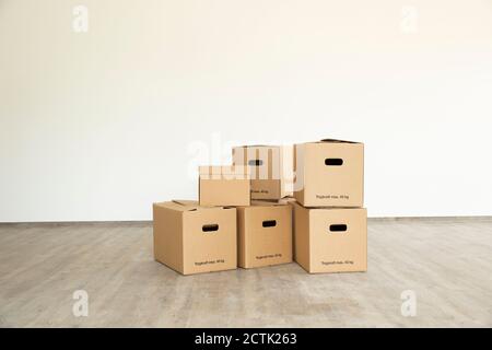Cardboard boxes on floor against white wall in new house Stock Photo