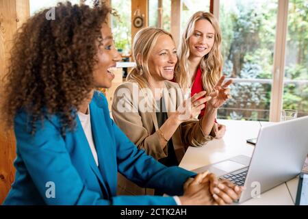 Cheerful female coworkers discussing business strategy at desk in office Stock Photo