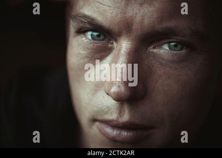 Close-up of thoughtful man with gray eyes against wall Stock Photo