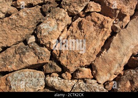 Rocky texture of a wall without mortar formed by irregular light brown stones Stock Photo