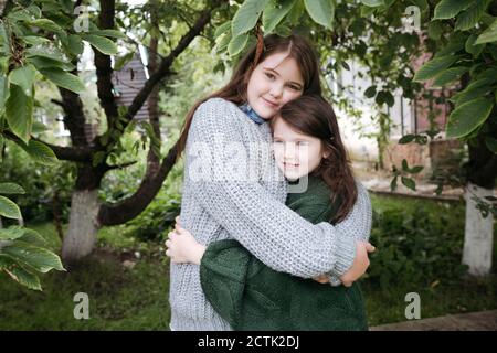 Sisters embracing each other in back yard Stock Photo