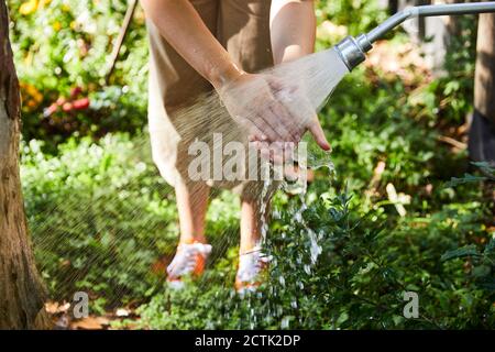 Woman washing hands under faucet in back yard Stock Photo