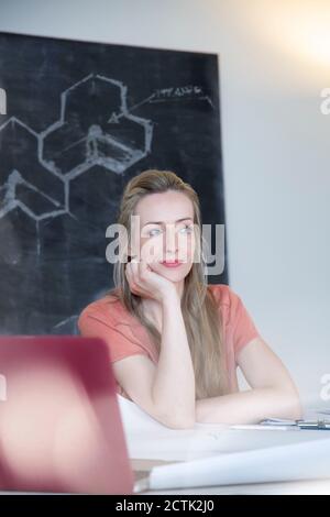 Thoughtful woman sitting at desk in home office Stock Photo