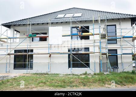 Construction worker sitting on scaffold at construction site Stock Photo