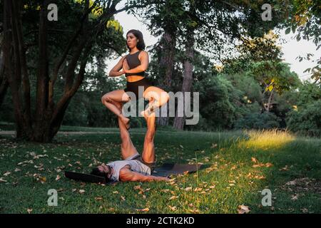 Male balancing female athlete on legs while practicing acroyoga in park Stock Photo