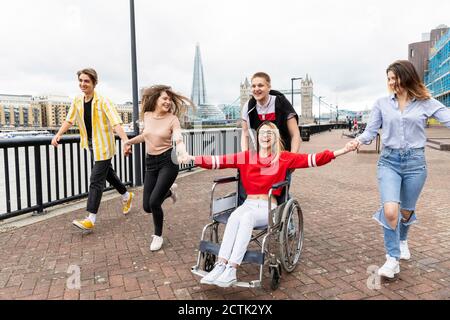 Cheerful men and women with disabled female friend enjoying in city, London, UK Stock Photo