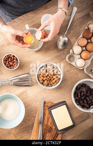 Woman separating egg white and egg yolk while standing at kitchen island Stock Photo