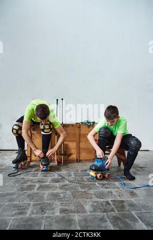 Father and son wearing roller skates by wooden box against wall at court Stock Photo