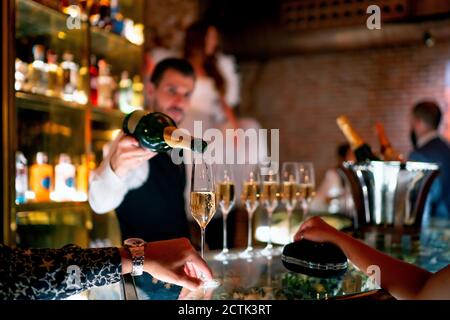 Bartender serving drink to man and woman at bar counter in pub Stock Photo