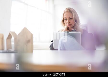 Serious female entrepreneur using digital tablet at desk in home office Stock Photo