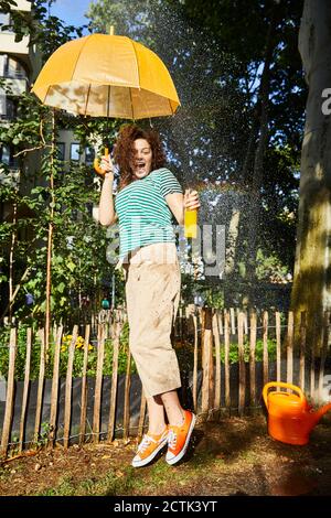 Young laughing woman with umbrella and limonade in garden Stock Photo