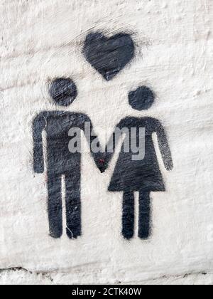 Simple graffiti depicting heart above heterosexual couple holding hands Stock Photo