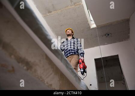 Construction worker holding power tool while walking in renovating house Stock Photo