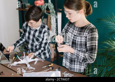 Siblings using digital tablet while preparing drone on table at home Stock Photo