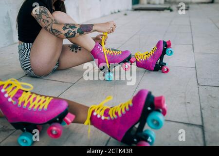 Low Section of friends with roller skates sitting on footpath Stock Photo