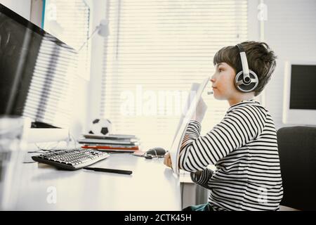Boy showing his home schooling results to webcam on computer, video conference Stock Photo