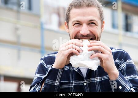 Close-up of construction worker eating bread while sitting at construction site Stock Photo