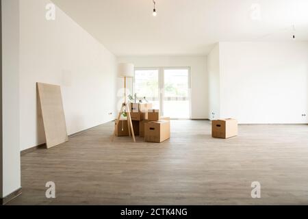 Electric lamp with cardboard boxes on hardwood floor in new house Stock Photo
