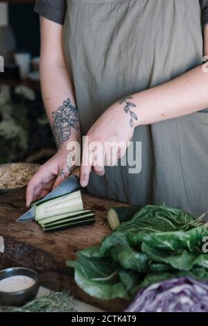 Young woman cutting cucumber on cutting board Stock Photo