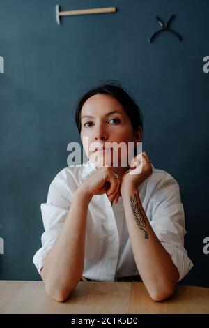 Serious woman sitting at table against wall in coffee shop Stock Photo