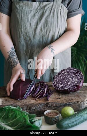 Young woman cutting red cabbage on cutting board Stock Photo