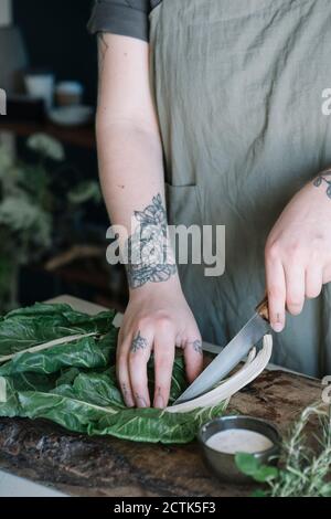 Young woman cutting pak choi on chopping board Stock Photo