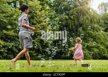 Brother and sister playing with bubbles in park Stock Photo