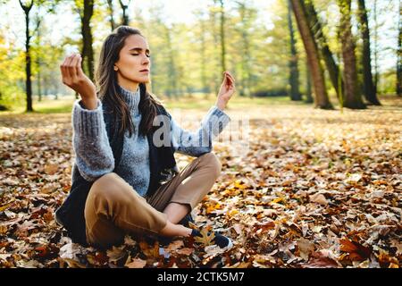 Young woman meditating in autumn forest Stock Photo