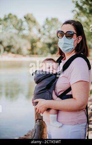 Mother and baby girl in baby carrier in park Stock Photo