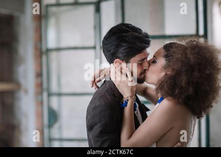 Just married couple kissing each other while standing at room Stock Photo